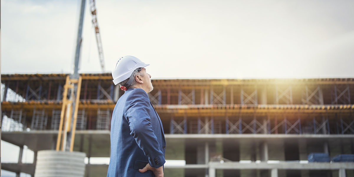 Photo of man with construction hat looking at construction site